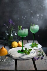 Sparkling Woodruff Drink in a glass . green woodruff drink with ice cubes on black background.