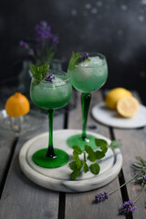 Sparkling Woodruff Drink in a glass . green woodruff drink with ice cubes on black background.