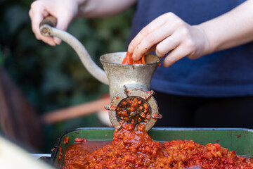 Close up outdoor on female hand on grinder mill for vegetables preparing paprika baked red pepper...