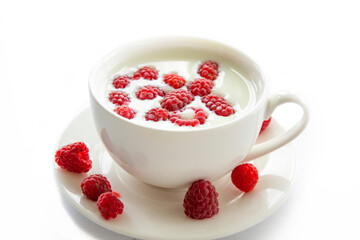 white mug with milk and raspberries in milk on a white background.