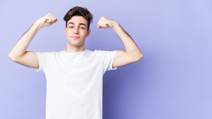 Young caucasian man isolated on purple background showing strength gesture with arms, symbol of feminine power