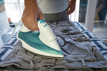 Ironing and steaming clothes with an iron. Pants and tennis shirt.