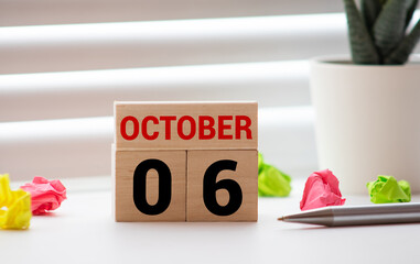 Cube shape calendar for October 06 on wooden surface with empty space for text.