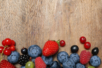 Different fresh berries on wooden table, flat lay. Space for text