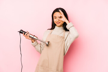 Young chinese woman holding a mixer isolated keeping a secret or asking for silence.