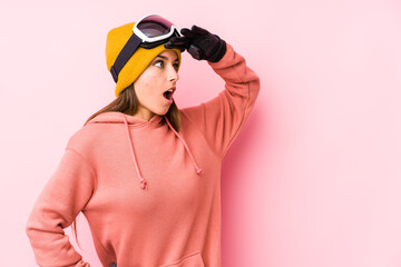 Young caucasian woman wearing a ski clothes isolated looking far away keeping hand on forehead.