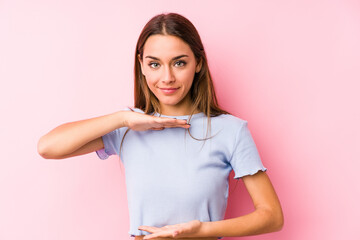 Young caucasian woman wearing a ski clothes isolated holding something with both hands, product presentation.