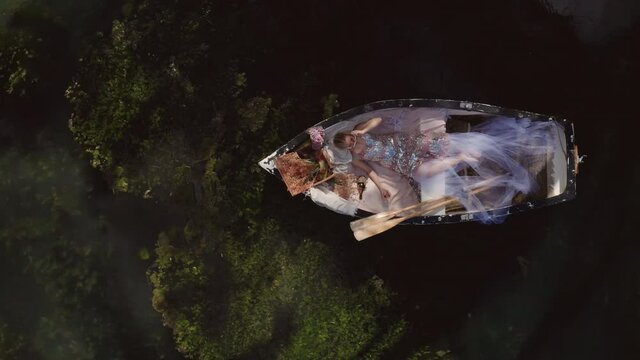 Fantasy Cosplay Concept of Beautiful Princess Woman Relaxing in RowBoat - Overhead Aerial Drone Top Down View