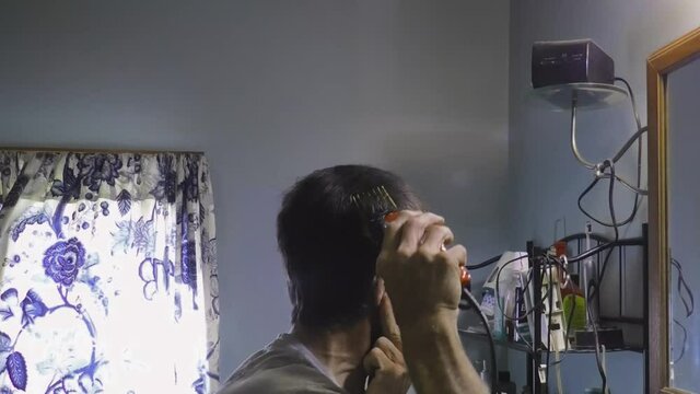 A Man Gives Himself a Haircut with Electric Clippers