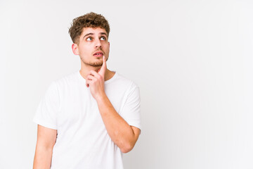 Young blond curly hair caucasian man isolated looking sideways with doubtful and skeptical expression.