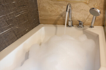 Interior of marble bathroom with bathtub full of foam bath