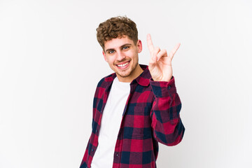 Young blond curly hair caucasian man isolated showing a horns gesture as a revolution concept.