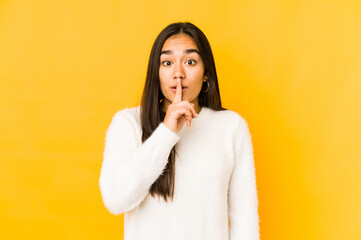 Young woman isolated on a yellow background keeping a secret or asking for silence.