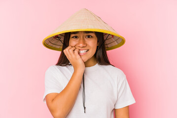 Young asian woman wearing a vietnamese hat isolated Young asian woman wearing a vietnamin hatbiting fingernails, nervous and very anxious.