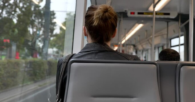Interior and selected focus view at the back of female passenger sit in light rail tram and wear face protection mask during epidemic of COVID-19 virus with new normal concept in Germany.
