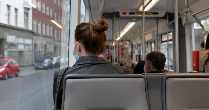 Interior and selected focus view at the back of female passenger sit in light rail tram and wear face protection mask during epidemic of COVID-19 virus with new normal concept in Germany.