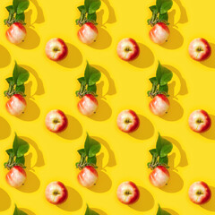 Seamless regular creative pattern from small red apples and green leaves with dark shadows.