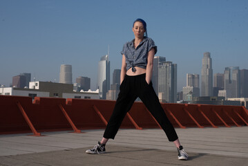 Tall young urban female enjoying the sunshine on a city rooftop overlooking Downtown Los Angeles.