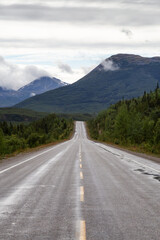 Naklejka premium Beautiful View of a scenic road in the Northern Rockies during a sunny and cloudy morning. Taken in British Columbia, Canada. Nature Background