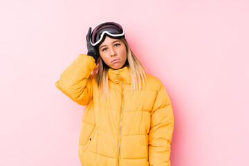Young caucasian woman wearing a ski clothes in a pink background being shocked, she has remembered important meeting.