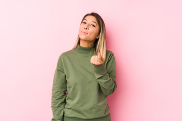 Young caucasian woman posing isolated  pointing with finger at you as if inviting come closer.