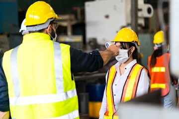 Temperature measurement with employee temperature meter before entering work at factory. Professional engineering team.
