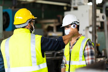 Temperature measurement with employee temperature meter before entering work at factory. Professional engineering team.