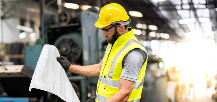 Portrait of mechanical worker working on blueprint. Bearded man worker in building helmet or hard hat for safety.