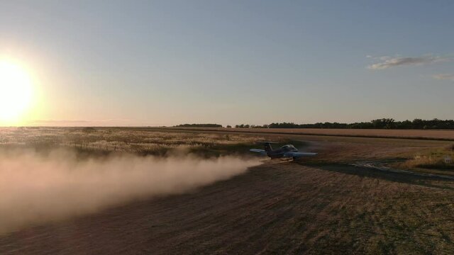 Aero L-29 Delfin Jet plane starting, is about to launch from field, making cloud of dust by turbine engine against sunset light, aerial shot