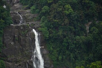 Arial view of a High waterfall in the green forest. stream of water falling down in the middle. Rain forest in Sri Lanka, as a natural concept of travel photography.