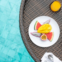 Floating Breakfast tray in swimming pool at luxury hotel or tropical resort villa, fruits; mango,...