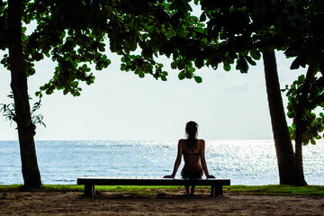 Naklejka na ściany i meble Woman relaxing on a beach bench. Summer vacation