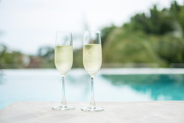 Two sparkling champagne glasses or prosecco near swimming pool. Summer travel, vacation, holiday and weekend concept