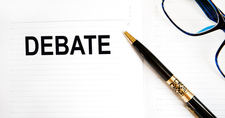 The inscription on the sheet from the diary DEBATE, next crumpled leaves from notes, glasses and pencil.