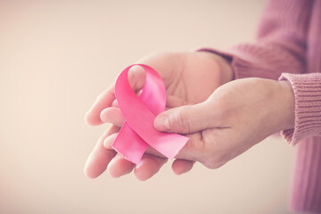 woman wearing pink top with pink ribbon, breast cancer awareness, October pink, World cancer day concept