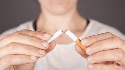 girl holding a broken cigarette in half close-up, harm from smoking, no smoking concept, bad habit, harm from nicotine