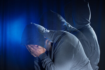 A multiple exposure of a man depicting stages of suffering. The man wears a shirt with a hood in...