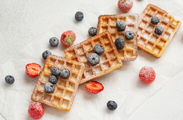 Belgium waffles with fresh berries and caster sugar on white background. Traditional waffles with strawberries and blueberries. Delicious breakfast. Selective focus