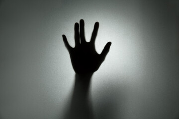 Ghost concept shadow of hand behind the matte glass blurry hand and body soft focus.