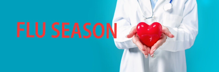 Flu Season Coronavirus theme with a doctor holding a heart on a blue background