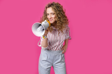 Young woman speaks into a megaphone. Isolated pink background.