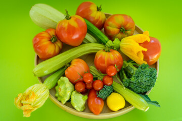 Plate with fresh vegetables on green background