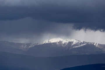 Fototapeta na wymiar mountain pick with snow and heavy clouds in winter season in Ioannina Greece