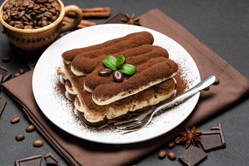 Classic tiramisu dessert on ceramic plate on dark concrete background