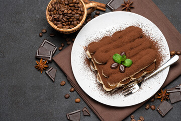 Classic tiramisu dessert on ceramic plate on dark concrete background