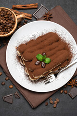 Classic tiramisu dessert on ceramic plate on dark concrete background
