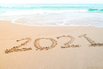Fototapeta na wymiar 2021 year hand drawn on sand summer beach.