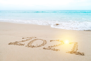2021 year hand drawn on sand summer beach.