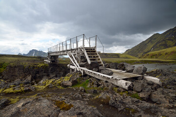 Wooden bridge crossing a river in Iceland secured by large rock boulders