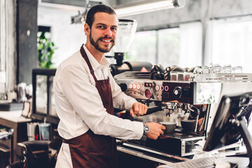 Portrait of handsome bearded barista man small business owner working using coffee machine for...